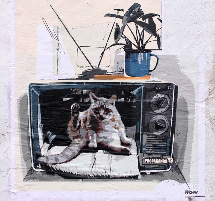 Художник нарисовал старый телевизор без экрана, а в нем — кота, поднявшего лапу. 